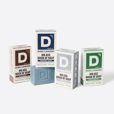 Four boxes of Duke Cannon Big Ass Bricks of soap on a white background. Scents present: Old Glory, Midnight Swim, Gunsmoke and High Country.