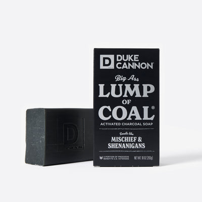Big Ass Brick of soap next to its packaging with 'Duke Cannon' branding on a white background. Big Ass Lump of Coal activated charcoal soap..