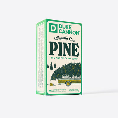 Big Ass Brick of soap inside of its packaging with 'Duke Cannon' branding on a white background. Illegally Cut Pine. With creative product description on the side.