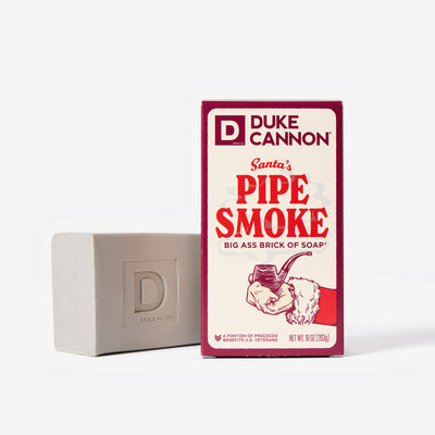 Big Ass Brick of soap next to its packaging with 'Duke Cannon' branding on a white background. Santa's Pipe Smoke.