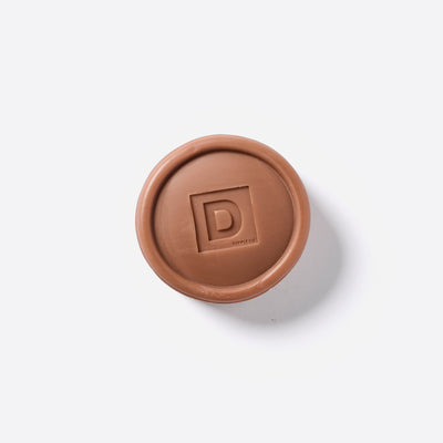 Puck shaped Bar of Soap with the Duke Cannon logo in the middle. 