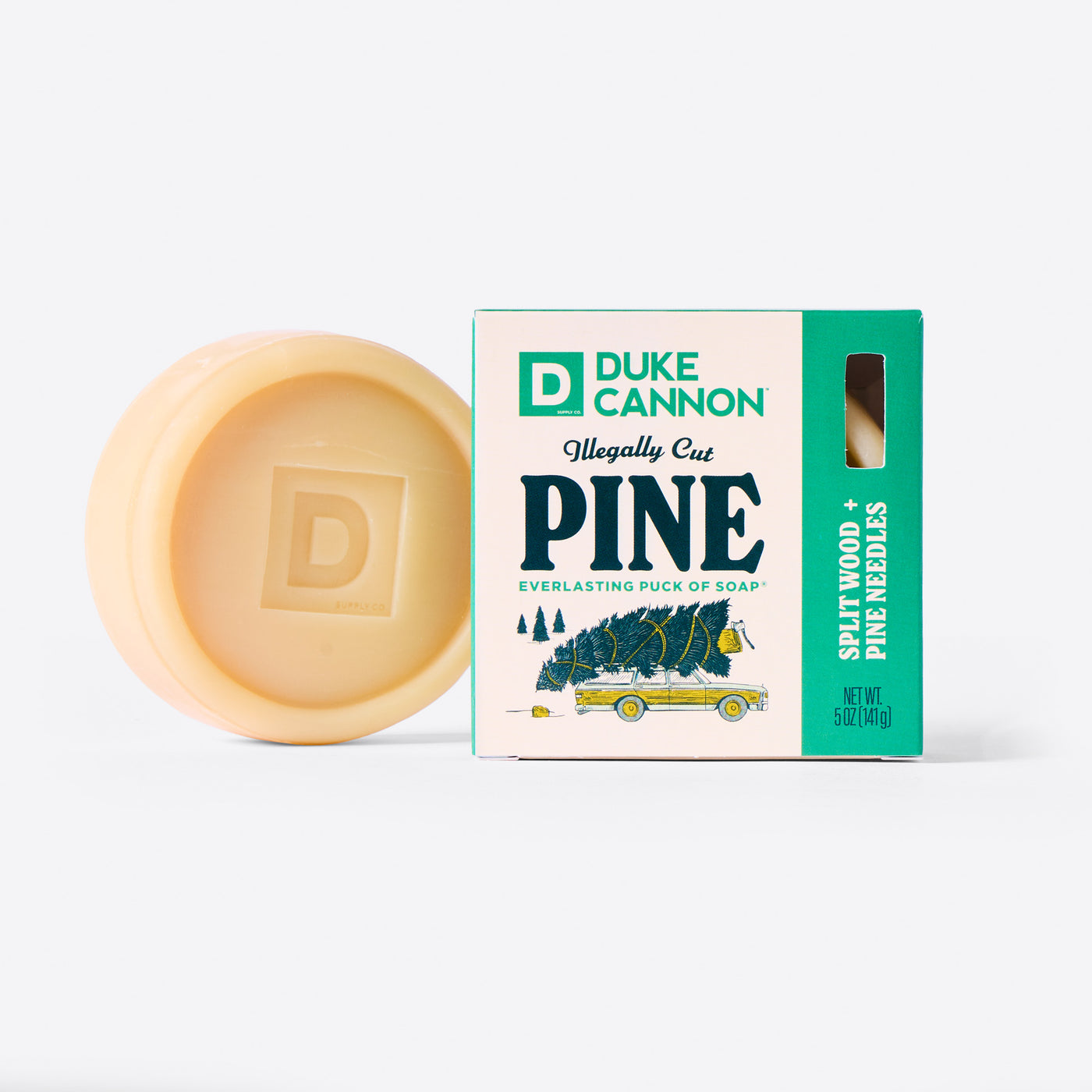 Duke Cannon Illegally Cut Pine Everlasting Puck of Soap next to it's packaging. On a white background. Scent is Splitwood + Pine Needles.