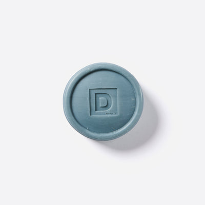 Round blue rubber puck of soap with a 'D' Duke Cannon logo on a white background