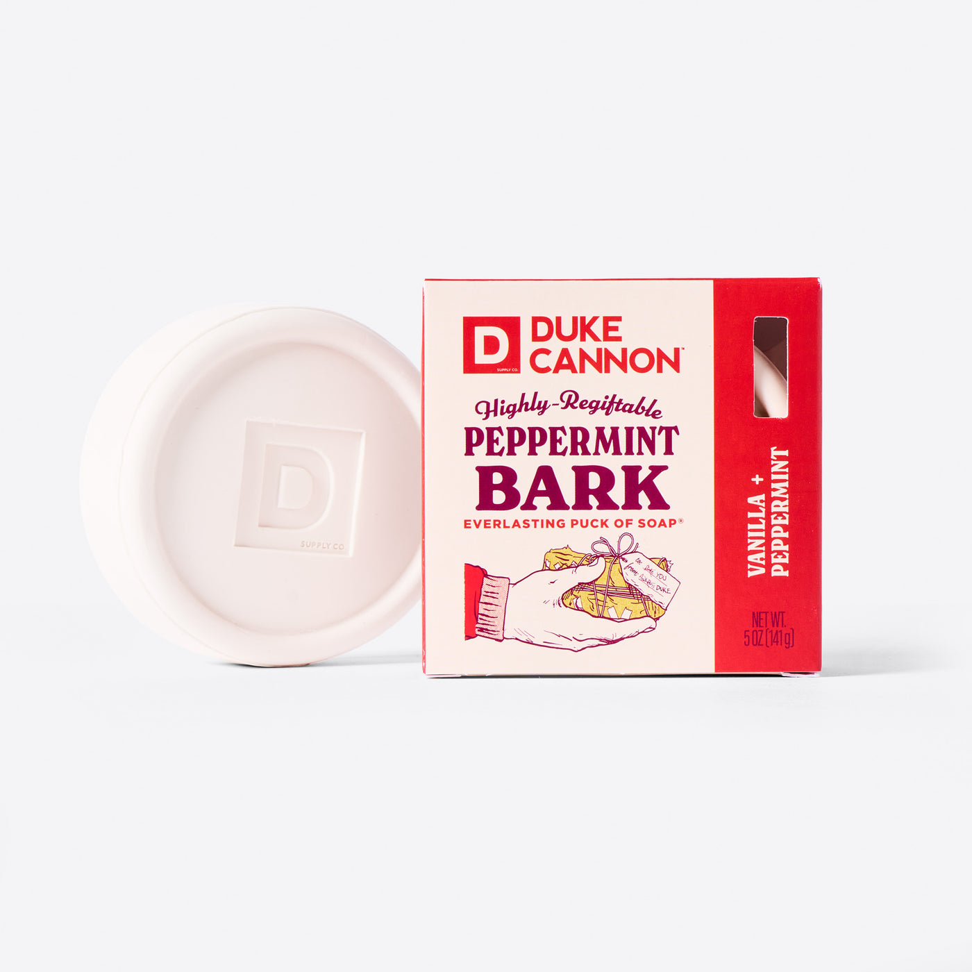 Duke Cannon Highly Regiftable Peppermint Bark Everlasting Puck of Soap next to it's packaging. On a white background. The soap puck itself is white. Scent is Vanilla + Peppermint.