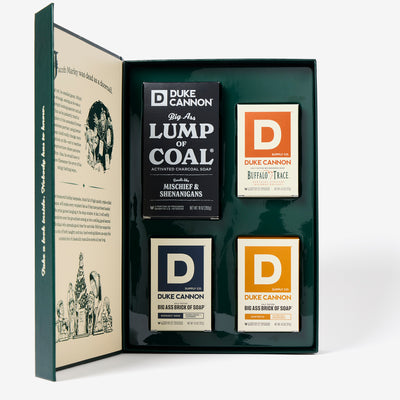 The inside of the Duke Cannon Naughty & Nice Bar Soap Gift Set with a Lump of Coal Bar, a  Midnight Swim Bar, a Sawtooth Bar and a Buffalo Trace Bourbon bar on a white background.